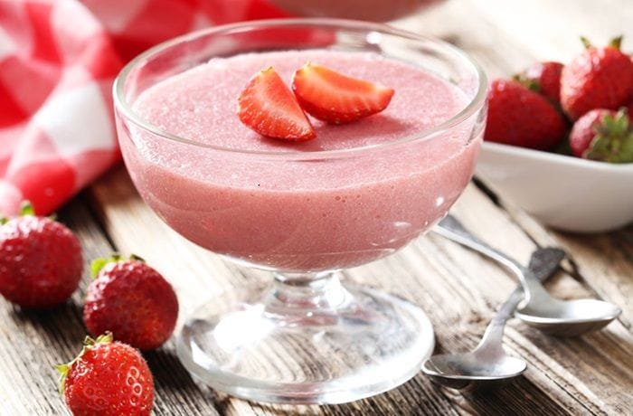 Pale pink strawberry yogurt gelatin in a glass decorated with fresh strawberries
