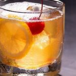 Amaretto sour cocktail served over ice with an orange slice and a maraschino cherry
