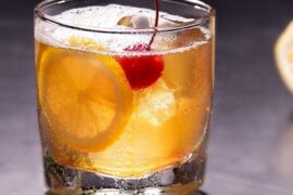 Amaretto sour cocktail served over ice with an orange slice and a maraschino cherry