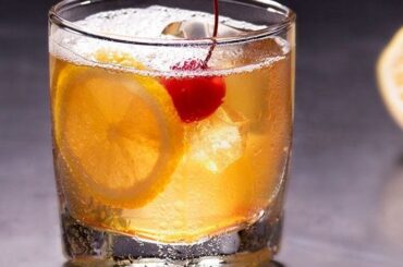 Amaretto sour cocktail served over ice with an orange slice and a maraschino cherry
