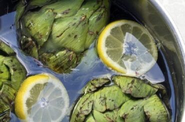Artichoke water in a glass pitcher with lemon slices and mint