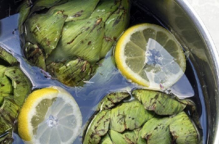 Artichoke water in a glass pitcher with lemon slices and mint