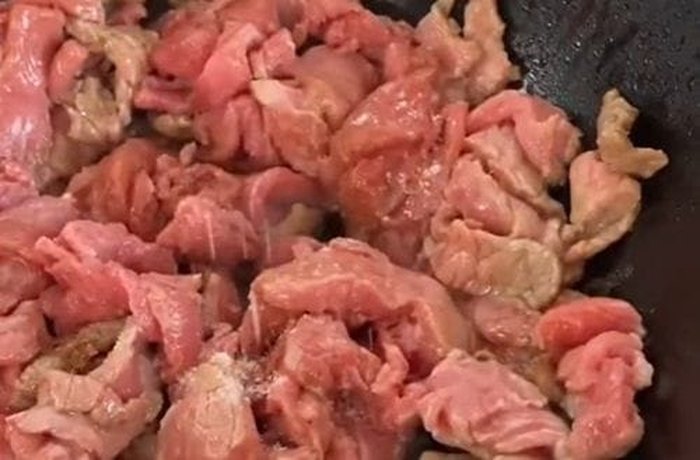Beef strips stir-fried in a wok for tallarín saltado