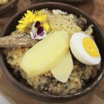 Chilean charqui chupe, dried beef and bread casserole topped with parmesan, in a clay bowl