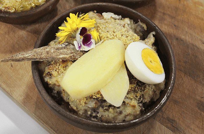 Chilean charqui chupe, dried beef and bread casserole topped with parmesan, in a clay bowl