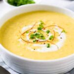 Chilean cream of corn soup in a bowl garnished with corn kernels and basil