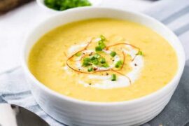Chilean cream of corn soup in a bowl garnished with corn kernels and basil