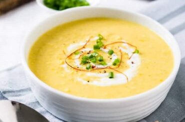 Chilean cream of corn soup in a bowl garnished with corn kernels and basil