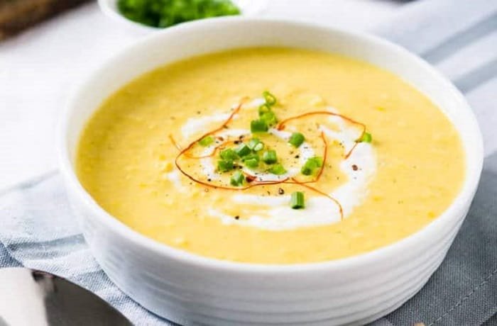 Chilean cream of corn soup in a bowl garnished with corn kernels and basil