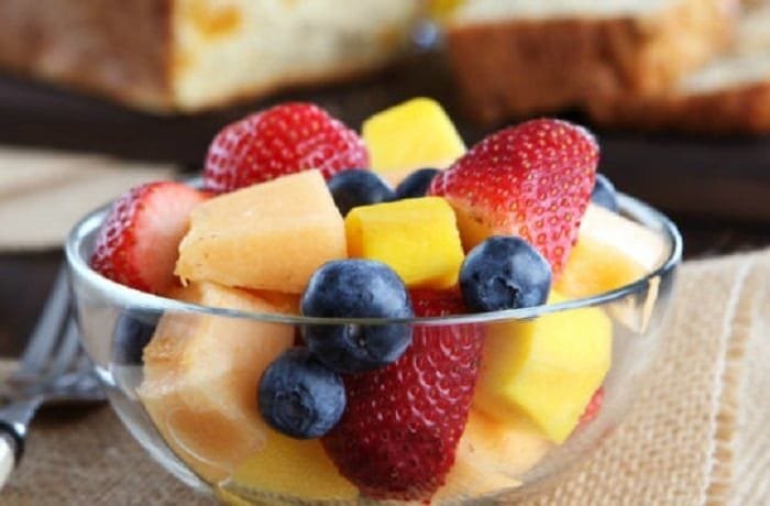 Chilean fresh fruit salad with strawberries, blueberries, apple, and orange topped with yogurt and honey