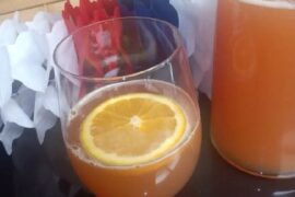 Chilean grape chicha with fresh orange juice served in a glass with an orange slice