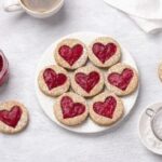 Chilean galletas delicias, round butter cookies sandwiched with strawberry jam showing through a cut out shape