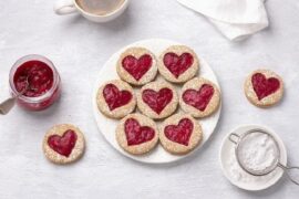 Chilean galletas delicias, round butter cookies sandwiched with strawberry jam showing through a cut out shape