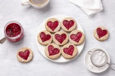 Chilean galletas delicias, round butter cookies sandwiched with strawberry jam showing through a cut out shape