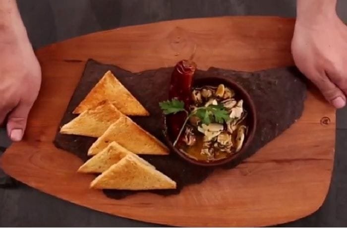 Chilean sea snails al pil pil with garlic and chili served in a clay bowl