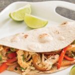 Chicken fajitas with bell peppers and red onion in flour tortillas
