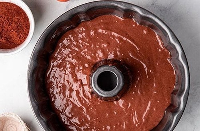 Chocolate cake batter in a loaf pan dusted with semolina, ready to bake