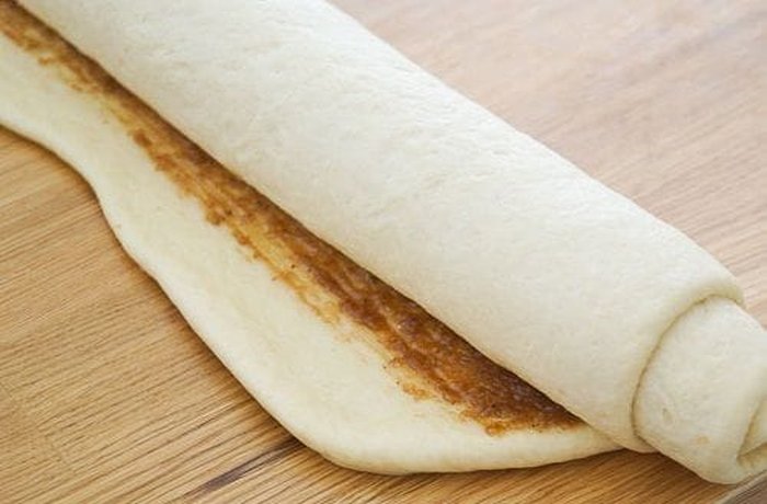 Dough spread with cinnamon sugar filling before rolling