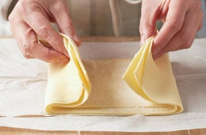 Folding the sugared puff pastry toward the center to shape palmeritas