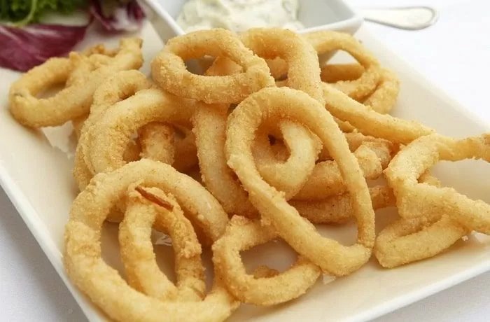 Crispy fried calamari rings with lemon wedges