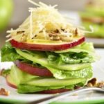 Stacked green salad with red and green apple slices, Parmesan, and walnuts