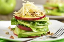 Stacked green salad with red and green apple slices, Parmesan, and walnuts