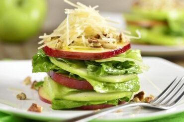 Stacked green salad with red and green apple slices, Parmesan, and walnuts