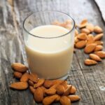 Homemade almond milk in a glass bottle with almonds