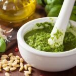 Homemade basil pesto in a mortar with pine nuts and parmesan