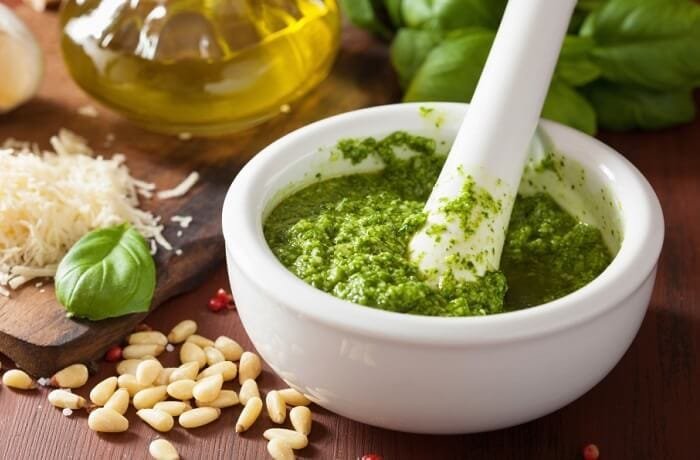 Homemade basil pesto in a mortar with pine nuts and parmesan