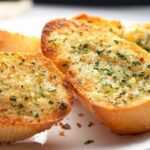 Homemade garlic and cheese bread slices with parsley on a baking tray