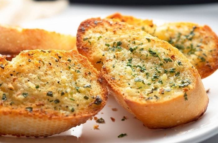 Homemade garlic and cheese bread slices with parsley on a baking tray