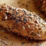Homemade multigrain bread loaves covered in oats and seeds, sliced to show the crumb
