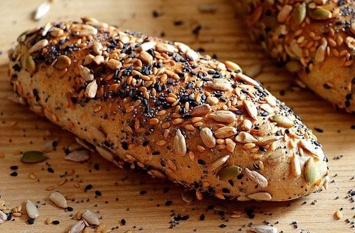 Homemade multigrain bread loaves covered in oats and seeds, sliced to show the crumb