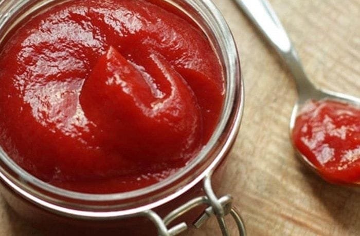 Homemade natural ketchup in a glass jar made from fresh tomatoes