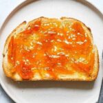 Homemade orange marmalade in a glass jar with fresh oranges