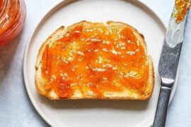 Homemade orange marmalade in a glass jar with fresh oranges