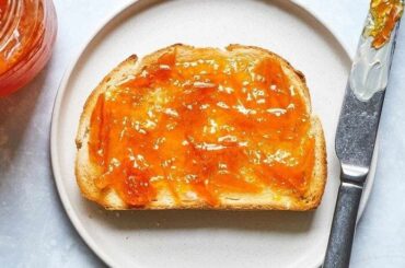 Homemade orange marmalade in a glass jar with fresh oranges