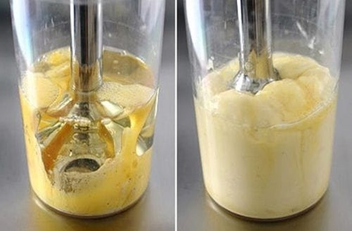 Egg and oil emulsifying into mayonnaise in the cup of an immersion blender