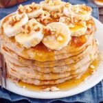 Stack of oat and banana pancakes with honey and fruit