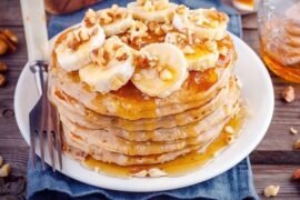Stack of oat and banana pancakes with honey and fruit