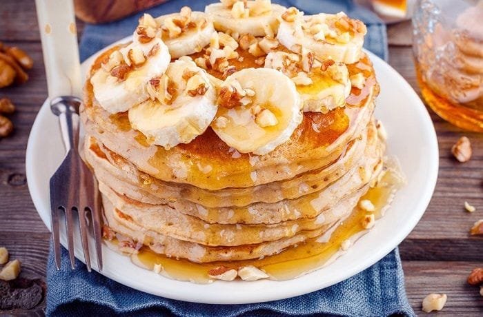 Stack of oat and banana pancakes with honey and fruit