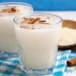 Homemade oat water in a pitcher with a cinnamon stick