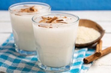 Homemade oat water in a pitcher with a cinnamon stick