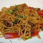 Peruvian beef tallarín saltado with red onion, tomato and scallions, homemade chifa noodle stir-fry