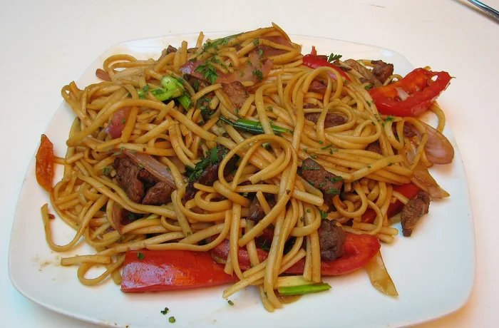 Peruvian beef tallarín saltado with red onion, tomato and scallions, homemade chifa noodle stir-fry
