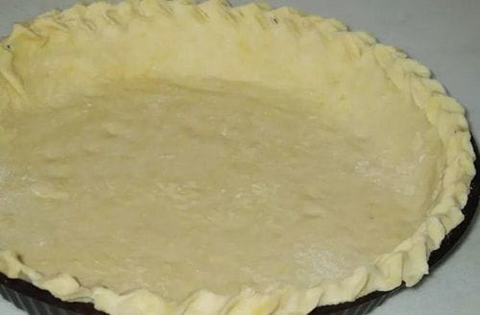 Quiche dough pressed into a buttered tart pan before blind baking