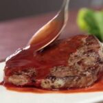 Glossy red wine sauce poured over sliced steak