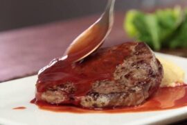 Glossy red wine sauce poured over sliced steak