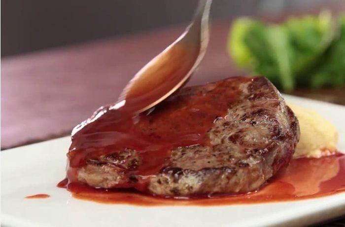 Glossy red wine sauce poured over sliced steak